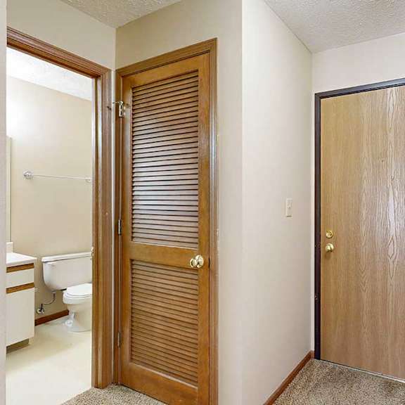 Thumbnail 3 of 33 A front door next to an open door to a hallway bathroom.