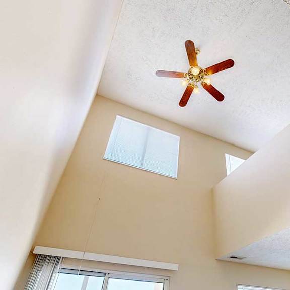 Thumbnail 13 of 33 A view of the loft area above from the living room, with two windows and a ceiling fan.