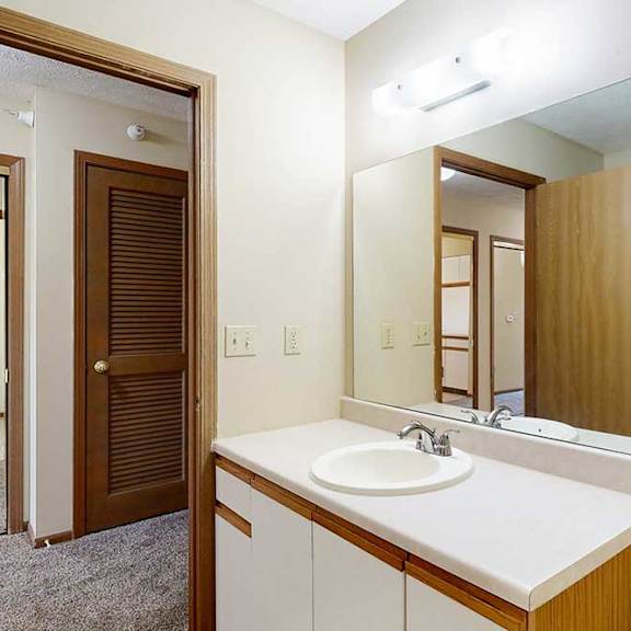 Thumbnail 18 of 21 A bathroom with white and oak cabinetry, a wide vanity sink, and a large mirror with overhead lighting.