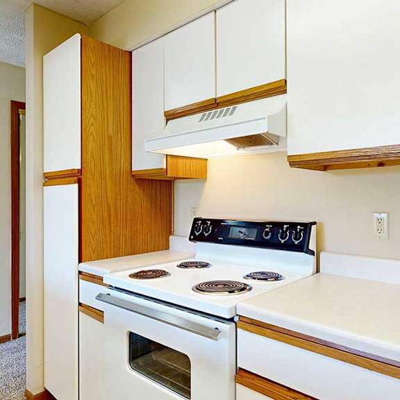 Thumbnail 6 of 21 A galley kitchen featuring white cabinets with oak trim and a white stove.