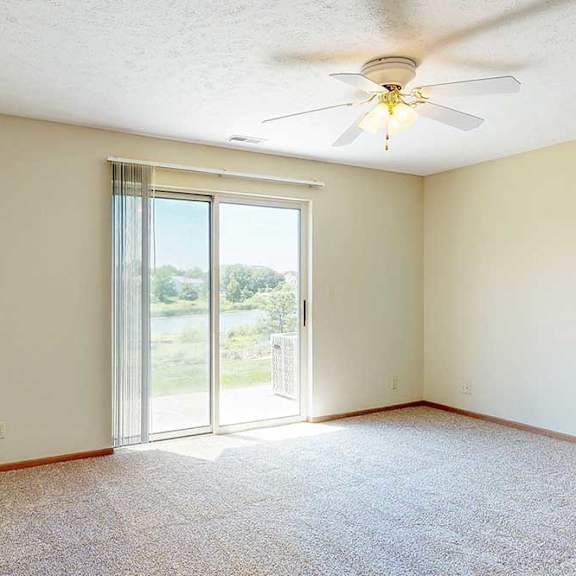 Thumbnail 12 of 21 A living area with a ceiling fan and a sliding glass door to a patio, providing plenty of natural light.