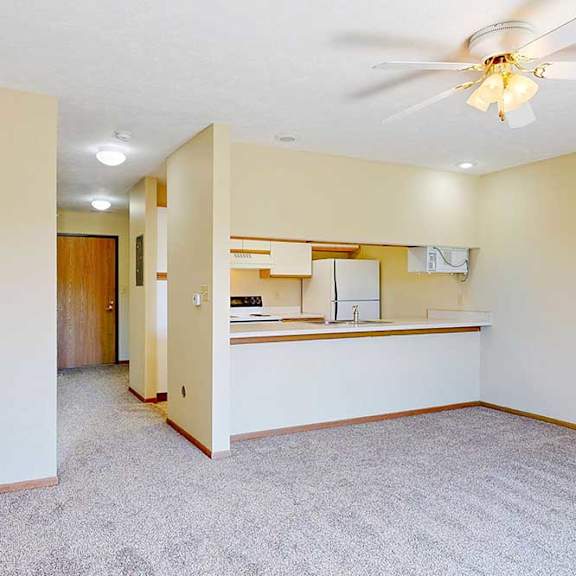Thumbnail 16 of 21 A living area with a ceiling fan and a counter with a passthrough window to the kitchen.