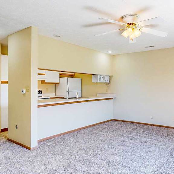 Thumbnail 10 of 21 A living area with a ceiling fan and a view of the kitchen.