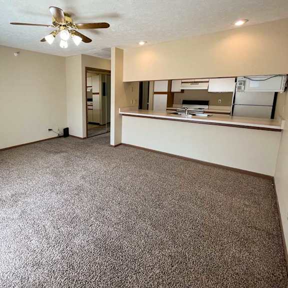 Thumbnail 6 of 13 a living room with a ceiling fan and carpeted floor