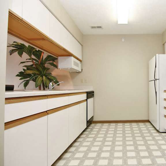 Thumbnail 7 of 13 A kitchen with white appliances and a plant on the counter.
