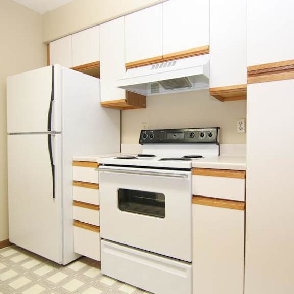 Thumbnail 8 of 13 A white kitchen with a refrigerator, oven, and stove.