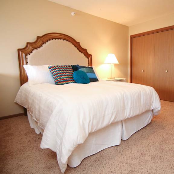 Thumbnail 9 of 13 A bed with a white comforter and a pillow with a blue design on it.