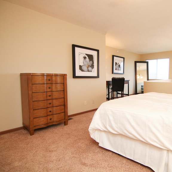 Thumbnail 10 of 13 A bedroom with a bed, dresser, and two framed pictures on the wall.