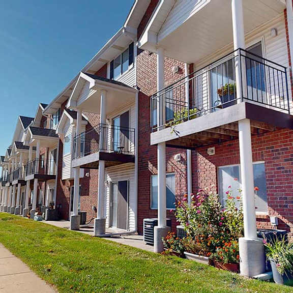 a red brick apartment building with white pillars and balconies with black metal railings