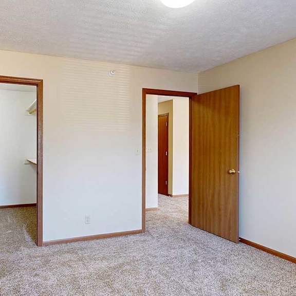 Thumbnail 25 of 29 A bedroom with a carpeted floor and a long walk-in closet.