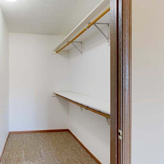Thumbnail 26 of 29 A long walk-in closet with two built-in shelves and hanging space to the right.
