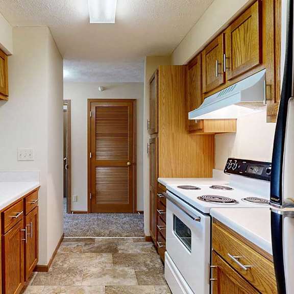 Thumbnail 19 of 29 A galley kitchen with wooden cabinets and a white appliances.