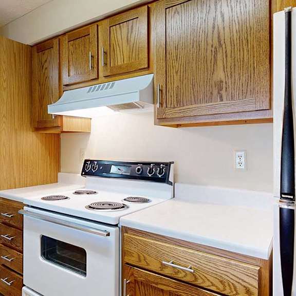 Thumbnail 17 of 29 A kitchen with a white appliances, a white countertop, and wooden cabinets.