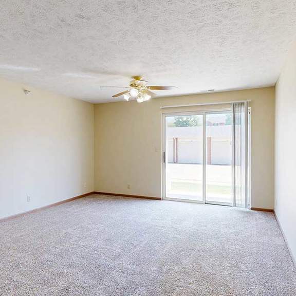 Thumbnail 20 of 29 A living room with a ceiling fan and sliding glass door.