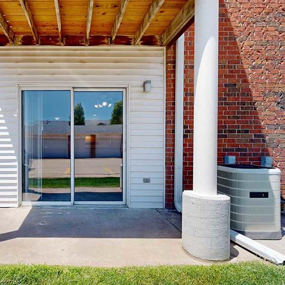 Thumbnail 22 of 29 A patio with two pillars, and a sliding glass door to a living room.