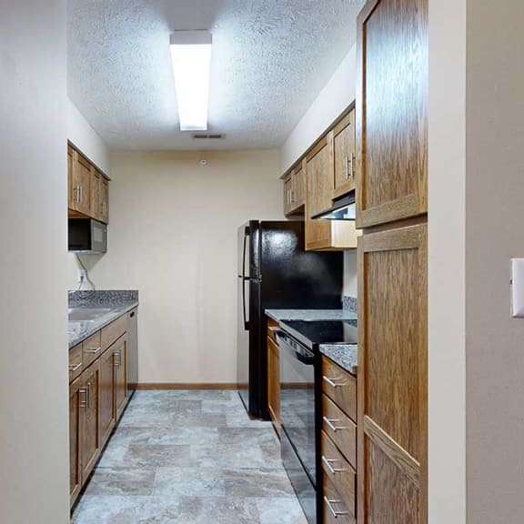 Thumbnail 6 of 20 a galley-style kitchen with wooden cabinets, black appliances, and a granite countertop