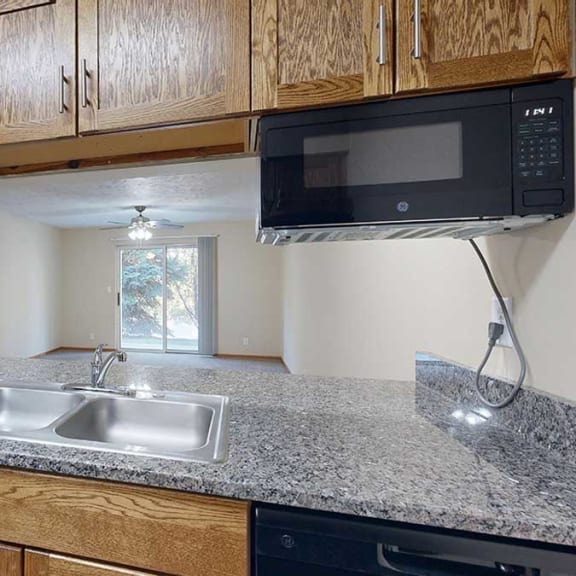 Thumbnail 7 of 20 a kitchen with granite countertops, a double-bowl sink, and a mounted microwave