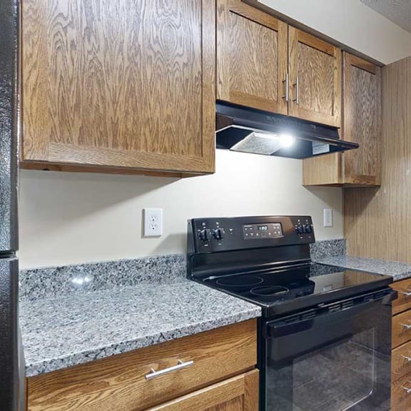 Thumbnail 5 of 20 a kitchen featuring wooden cabinets, granite countertops, and black appliances