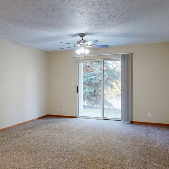 Thumbnail 12 of 20 a living room with carpet, a ceiling fan, and a sliding glass door to a patio