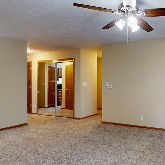Thumbnail 14 of 20 a living room with a ceiling fan and a hallway to the bedroom and bathroom