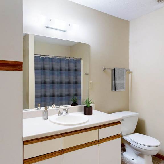 Thumbnail 11 of 29 A bathroom with a white toilet and a sink with a mirror above it.