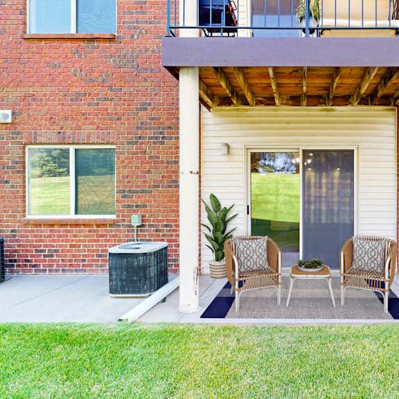 Thumbnail 12 of 29 A patio with a table and chairs is surrounded by a brick building.