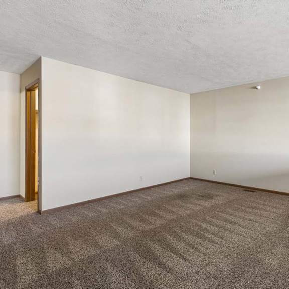 Thumbnail 14 of 16 Spacious apartment loft with neutral carpet, a half wall overlooking the living area below, and an open layout with access to the adjoining hallway.
