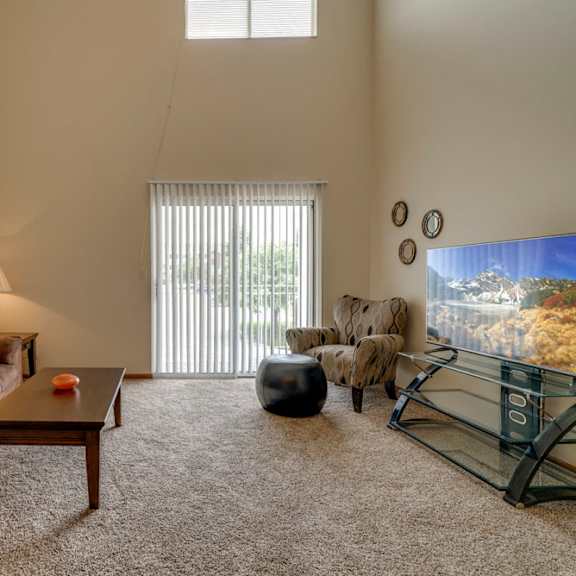 Thumbnail 3 of 15 Large windows and sliding doors provide lots of natural lighting in the living space at Pine Lake Heights Apartments