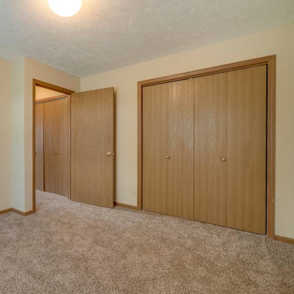 Thumbnail 12 of 15 A room with carpeted floor and two wooden doors.