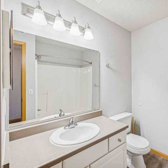 Thumbnail 28 of 29 A white bathroom with a sink, toilet, and mirror.