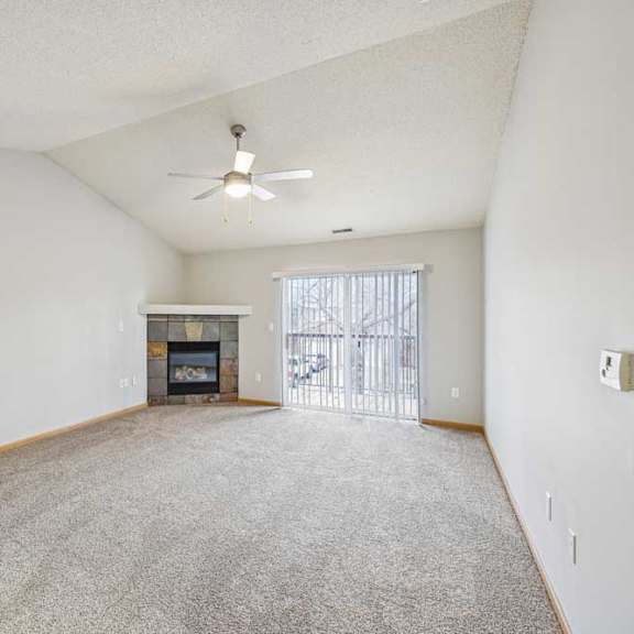 Thumbnail 3 of 13 A spacious living room with a fireplace and a ceiling fan.