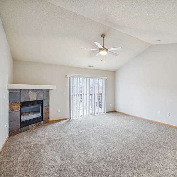 Thumbnail 9 of 13 A spacious living room with a fireplace and a ceiling fan.
