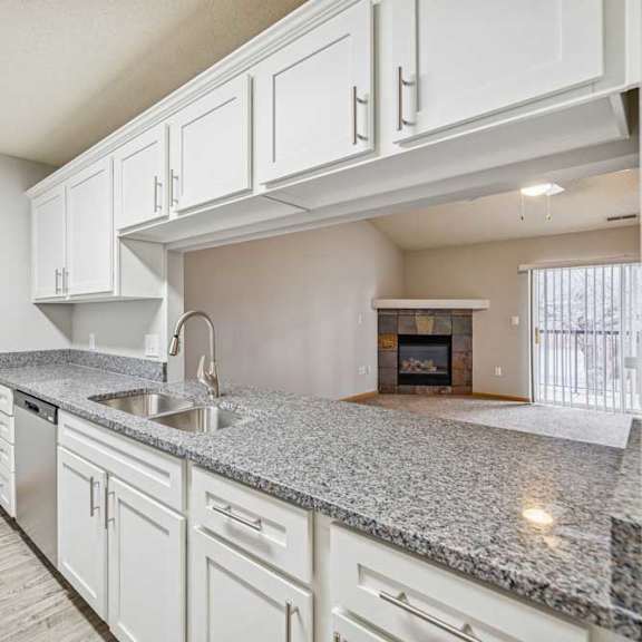 Thumbnail 5 of 13 A kitchen with granite countertops and white cabinets.