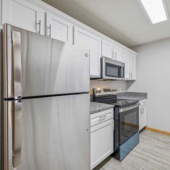 Thumbnail 2 of 13 A kitchen with a refrigerator, microwave, oven, and sink.