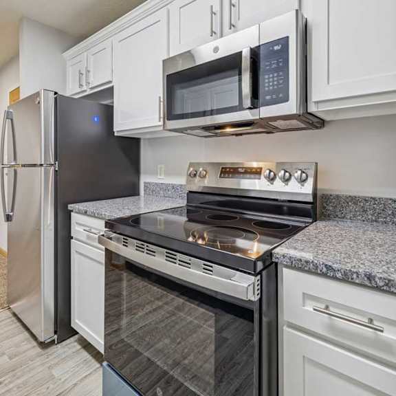 Thumbnail 7 of 13 A kitchen with a stove top oven and microwave above it.