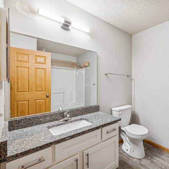 Thumbnail 13 of 13 A bathroom with a toilet, sink, and mirror.