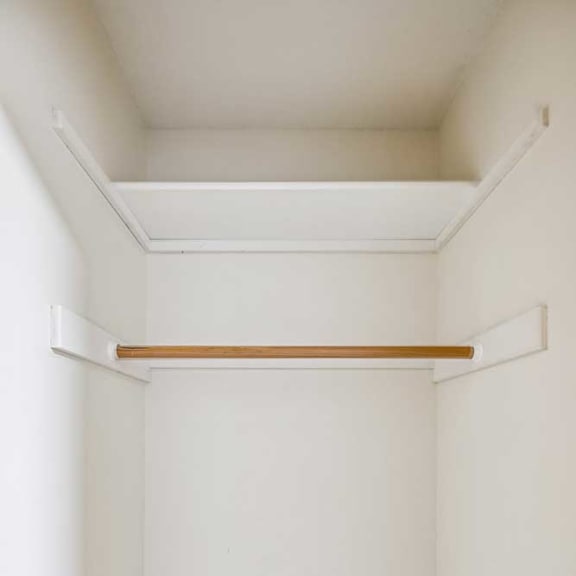 Thumbnail 8 of 13 A white wall with a shelf and a brown carpet.