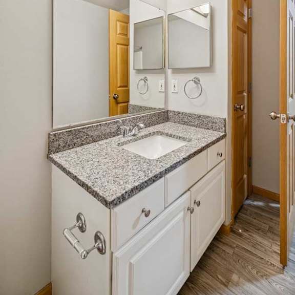 Thumbnail 31 of 40 A bathroom with a sink, mirror, and wooden door.
