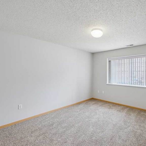Thumbnail 25 of 40 A room with a carpeted floor and a window with blinds.