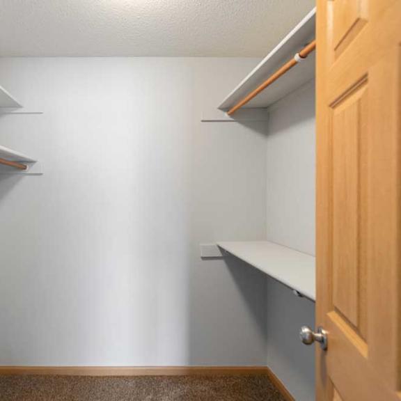 Thumbnail 30 of 40 A small, empty room with a wooden floor and a door on the right.