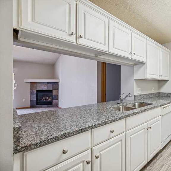 Thumbnail 33 of 40 A kitchen with white cabinets and a granite countertop.