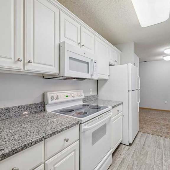 Thumbnail 27 of 40 A kitchen with white cabinets and appliances.