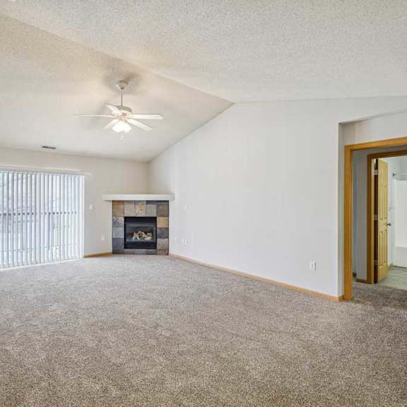 Thumbnail 22 of 40 A spacious living room with a fireplace and a ceiling fan.