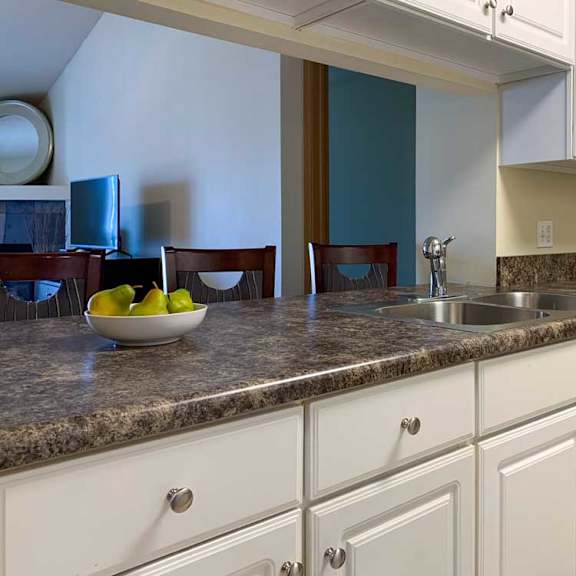 Thumbnail 18 of 20 a kitchen with white cabinets and a grey countertop, with a window to the living room