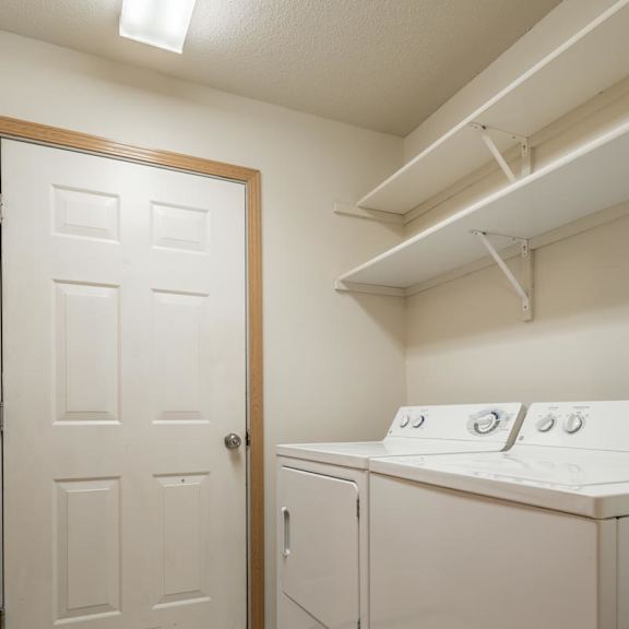 Thumbnail 3 of 11 A white laundry room with a door and a washer and dryer.
