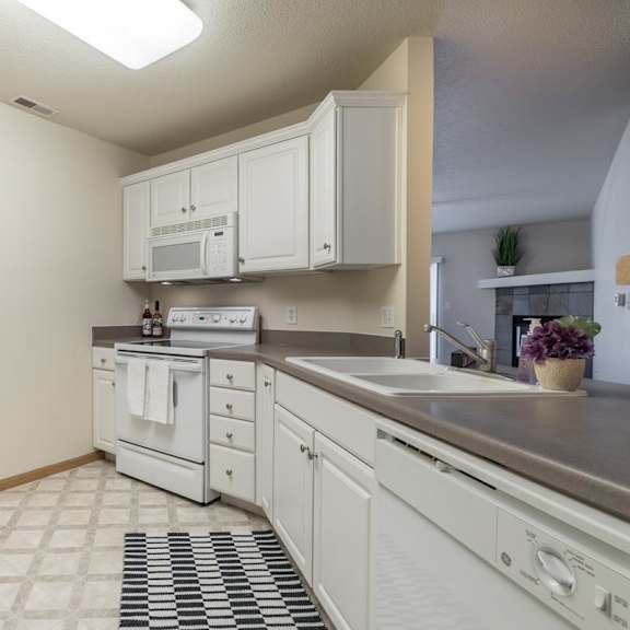 Thumbnail 4 of 11 A kitchen with white cabinets and appliances.