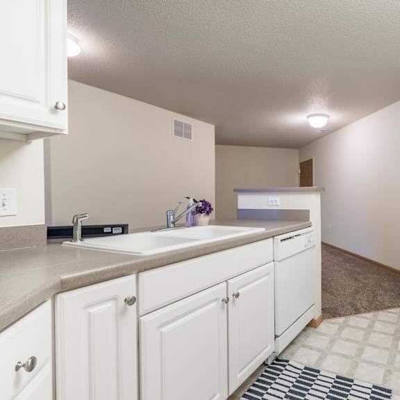 Thumbnail 6 of 11 A kitchen with white cabinets and appliances.