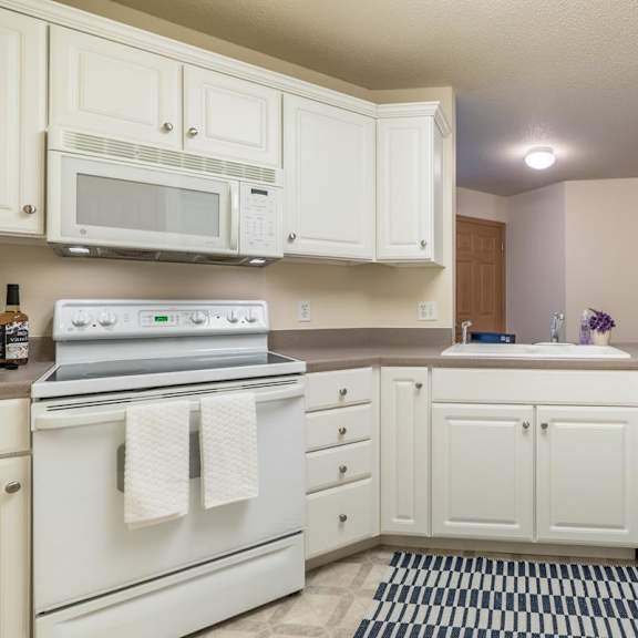 Thumbnail 5 of 11 A kitchen with white appliances and cabinets.
