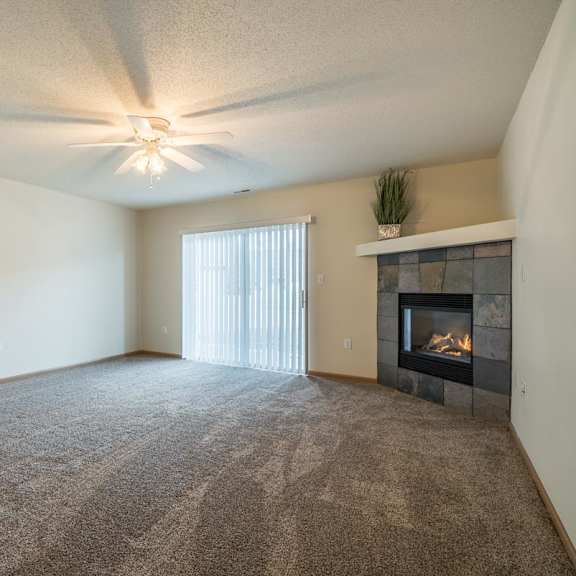 Thumbnail 7 of 11 A living room with a fireplace and a ceiling fan.