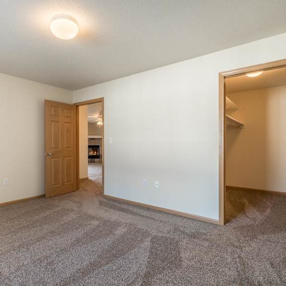 Thumbnail 9 of 11 A room with a carpeted floor and a door leading to another room.